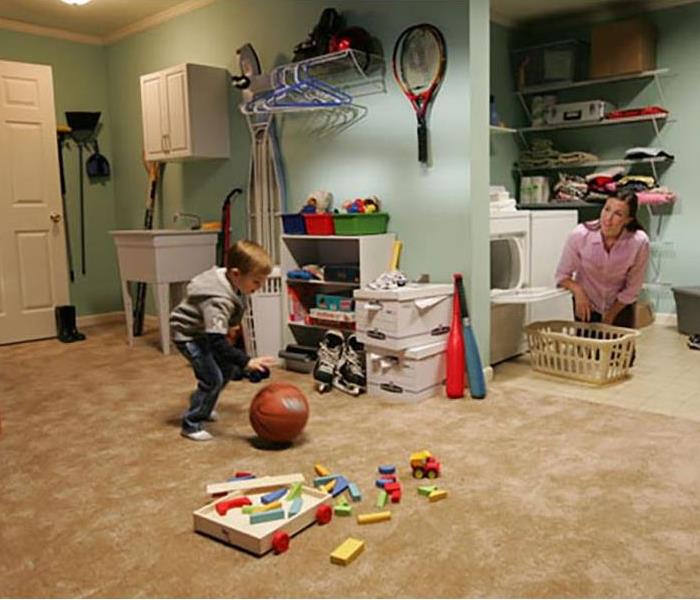 A clean basement, playroom and laundry room with a child playing 