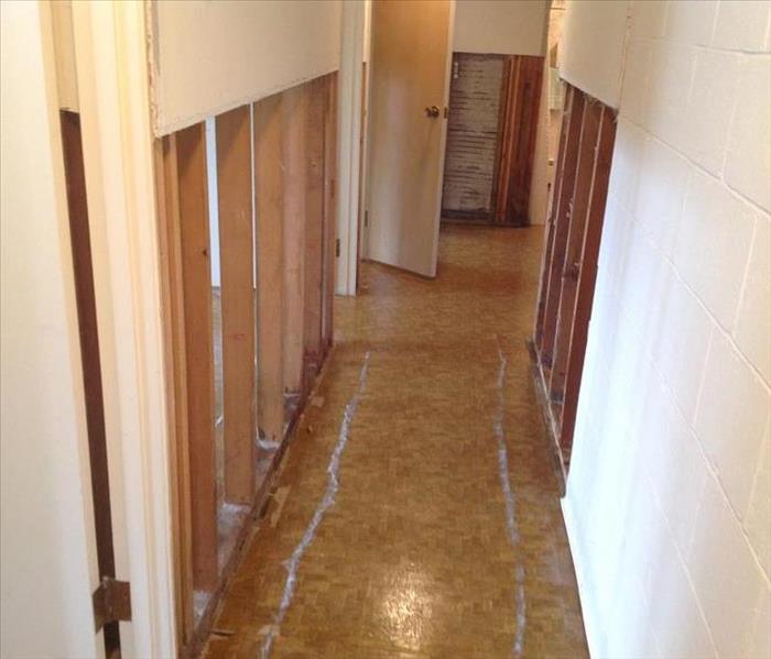 Damaged hallway, the sheetrock has been cut from the floor and drying equipment is in place.